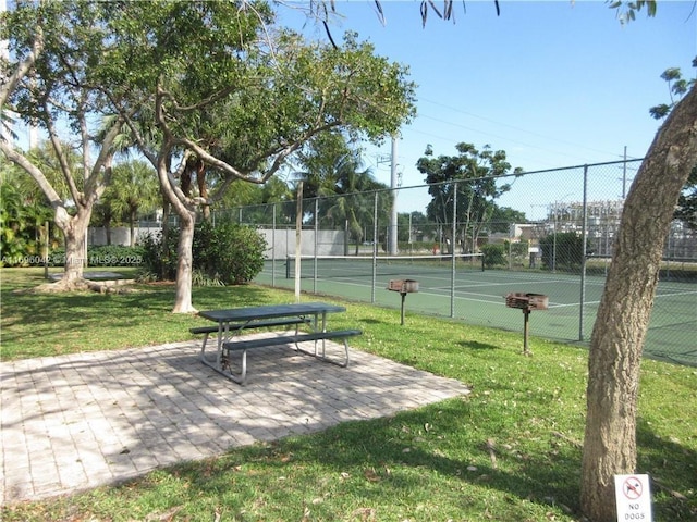 view of property's community featuring a lawn and tennis court