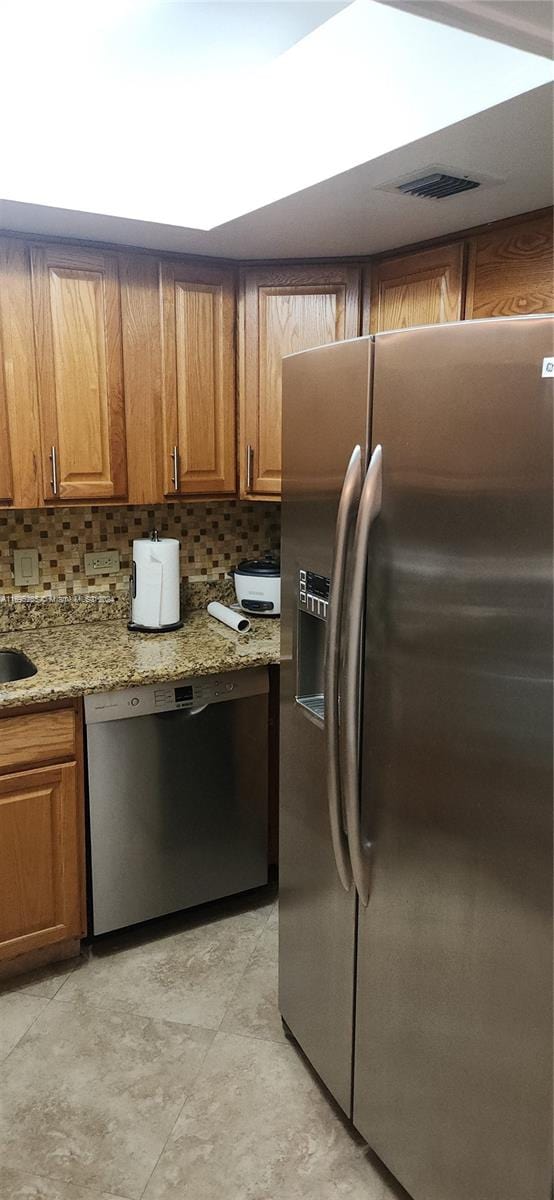 kitchen with light stone countertops, decorative backsplash, and stainless steel appliances