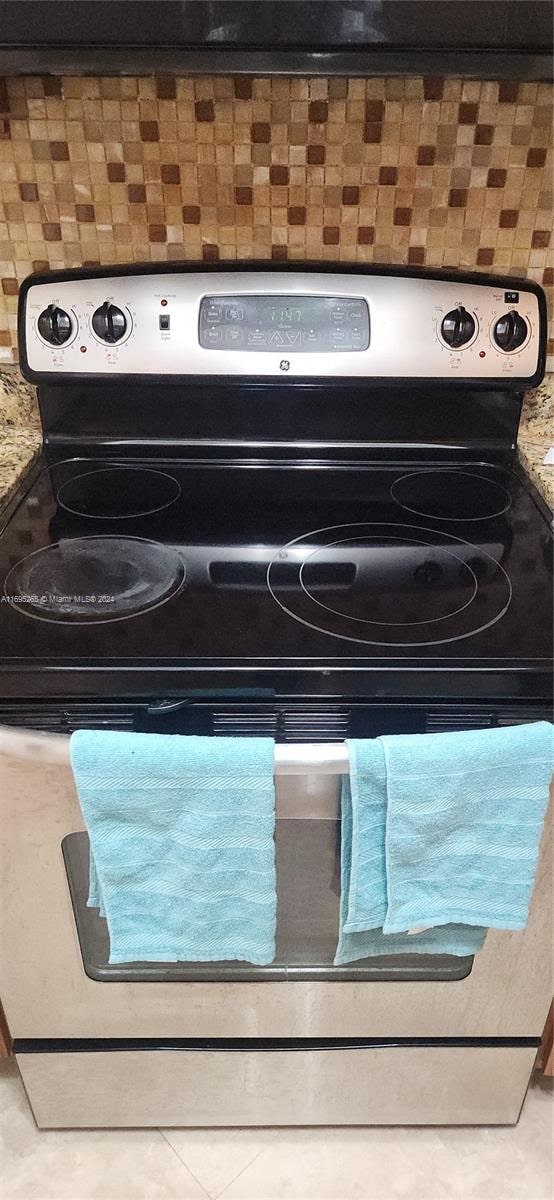 interior details featuring stone counters, electric range, and backsplash