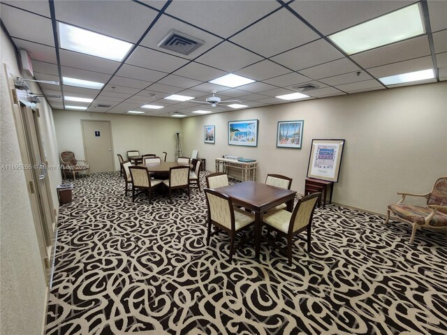 carpeted dining space with a drop ceiling and ceiling fan