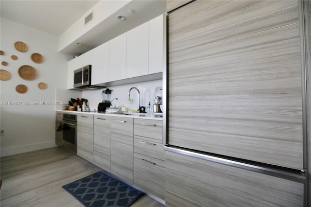 kitchen featuring sink, white cabinets, light hardwood / wood-style floors, and appliances with stainless steel finishes