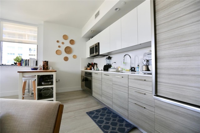 kitchen with white cabinets, appliances with stainless steel finishes, and light hardwood / wood-style floors