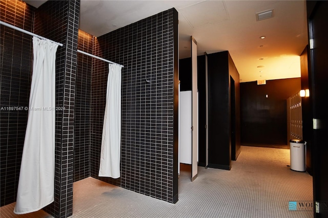 bathroom with a shower with shower curtain and tile walls