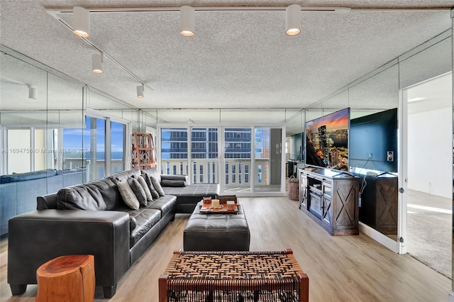 living room with a textured ceiling, a water view, and light hardwood / wood-style floors