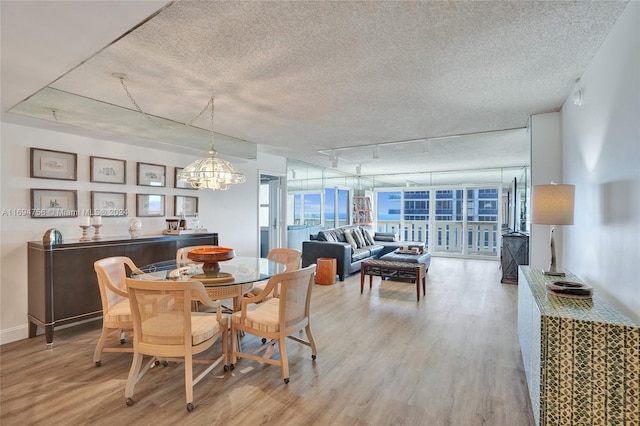 dining space with a textured ceiling, hardwood / wood-style flooring, an inviting chandelier, and track lighting