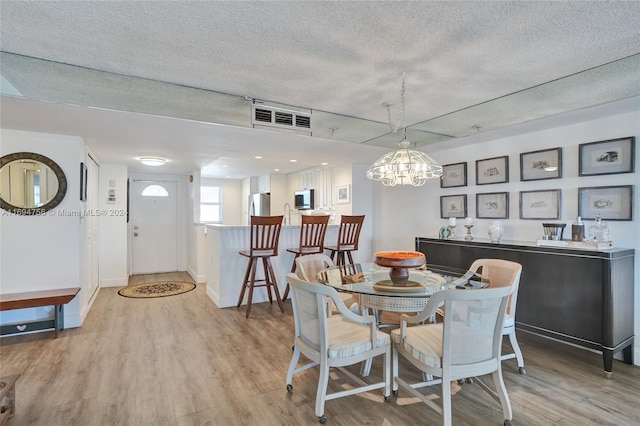 dining area featuring a textured ceiling and light hardwood / wood-style flooring