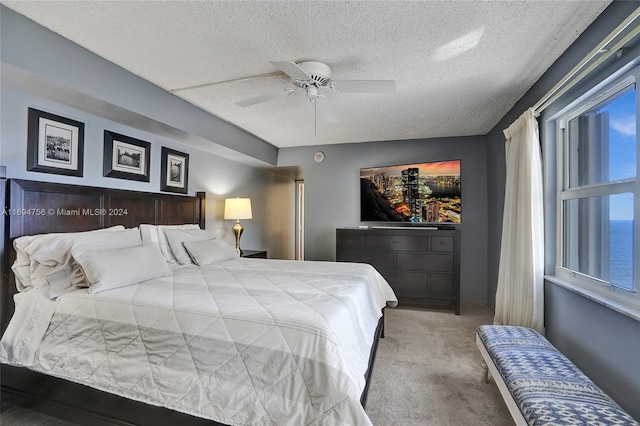 bedroom featuring light carpet, a textured ceiling, and ceiling fan