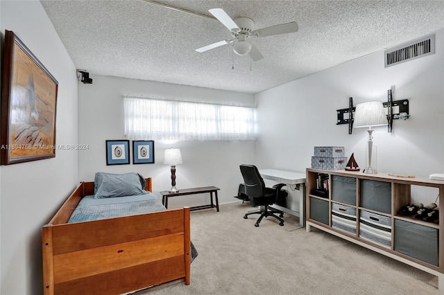 carpeted bedroom featuring ceiling fan and a textured ceiling