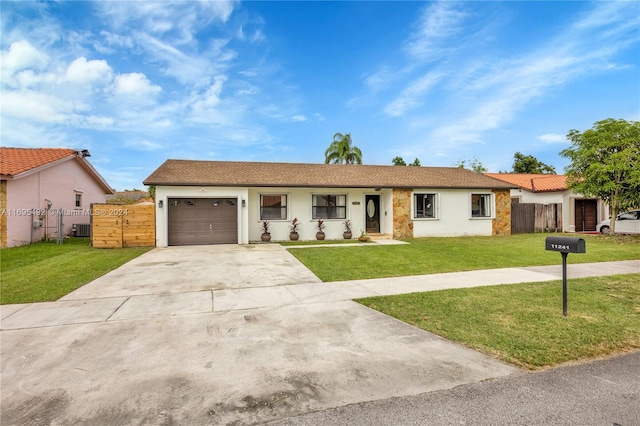 ranch-style home with a porch, a garage, a front lawn, and central air condition unit