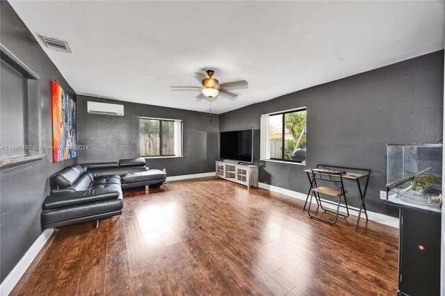 living room featuring ceiling fan, an AC wall unit, and dark wood-type flooring