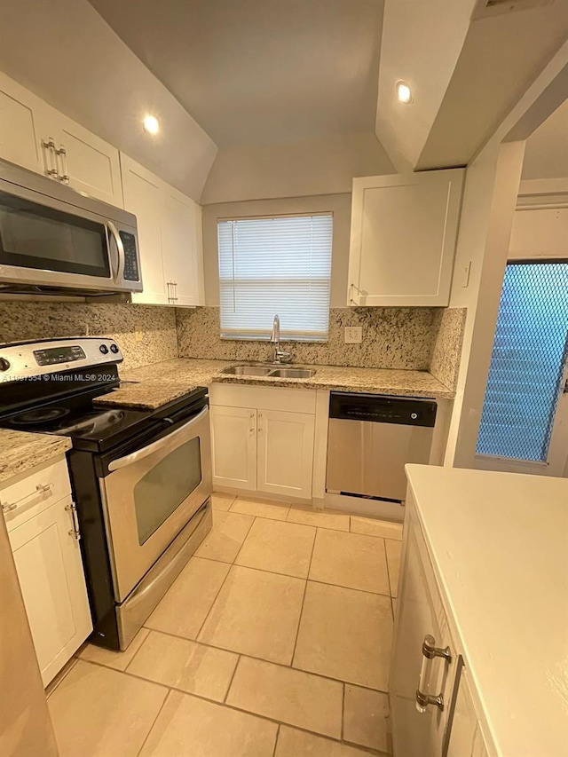 kitchen featuring lofted ceiling, white cabinets, sink, light tile patterned floors, and stainless steel appliances