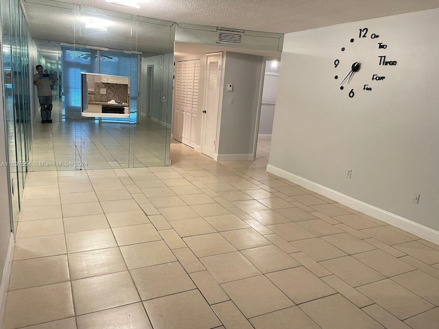 unfurnished room with light tile patterned flooring and a textured ceiling