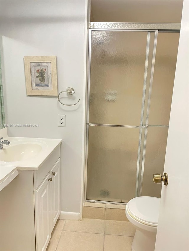 bathroom with tile patterned flooring, vanity, toilet, and a shower with door