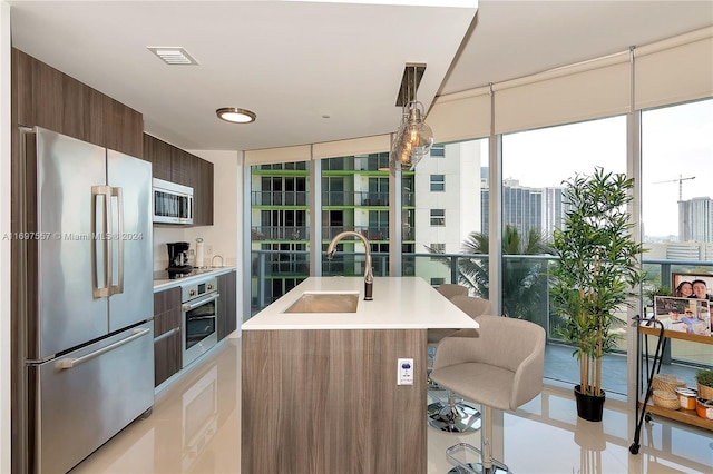 kitchen with a breakfast bar, sink, stainless steel appliances, and an island with sink