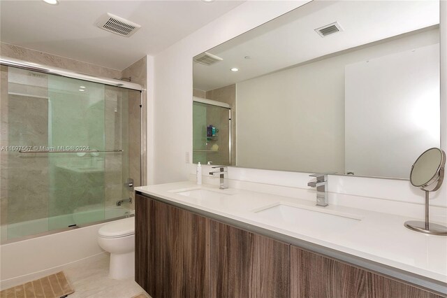 full bathroom with shower / bath combination with glass door, tile patterned floors, vanity, and toilet