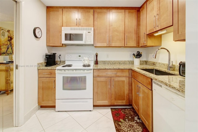 kitchen featuring light tile patterned flooring, white appliances, light stone counters, and sink