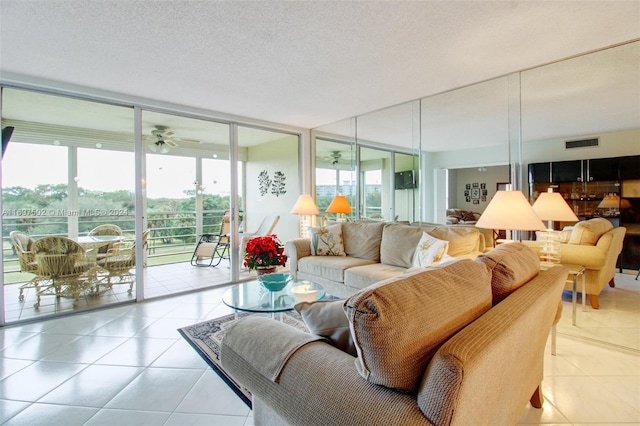 living room with ceiling fan, light tile patterned flooring, a textured ceiling, and a wall of windows