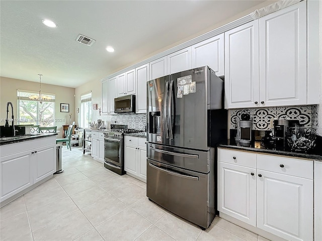 kitchen featuring white cabinetry, sink, stainless steel appliances, an inviting chandelier, and decorative backsplash