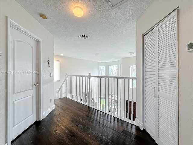 hallway with dark hardwood / wood-style flooring and a textured ceiling