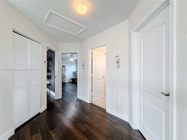 corridor with dark hardwood / wood-style flooring and a textured ceiling