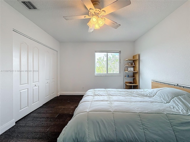 bedroom with a textured ceiling, dark hardwood / wood-style flooring, a closet, and ceiling fan