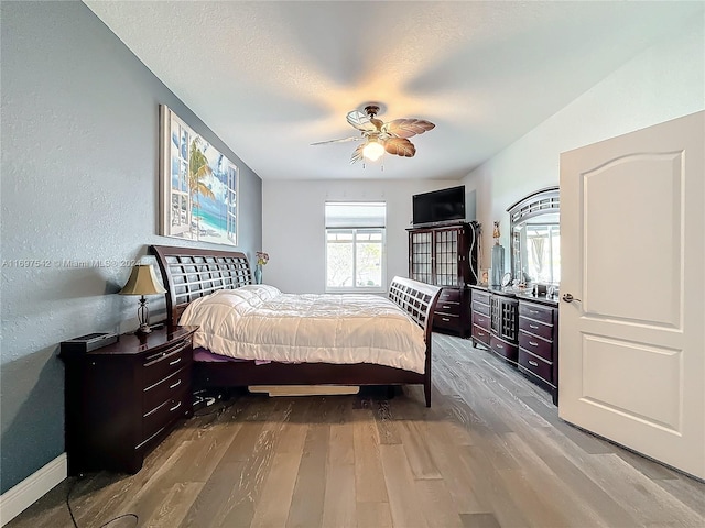 bedroom with ceiling fan, a textured ceiling, and light wood-type flooring