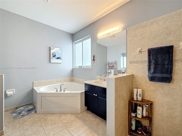 bathroom with tile patterned flooring, vanity, tile walls, and a tub