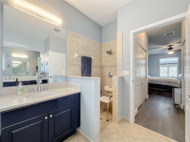 bathroom with ceiling fan, wood-type flooring, tiled shower, and vanity