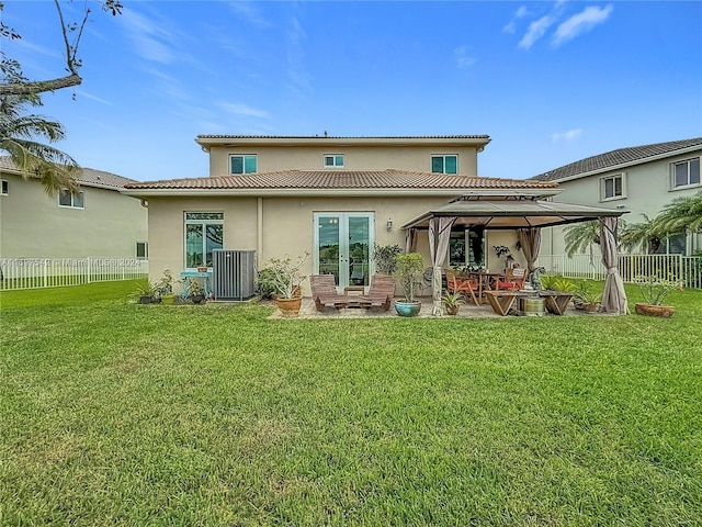 rear view of property featuring a gazebo, central AC unit, and a yard