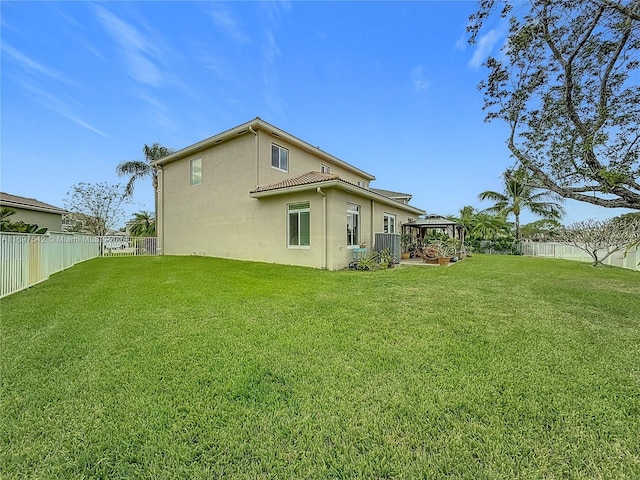 back of property featuring a gazebo and a lawn