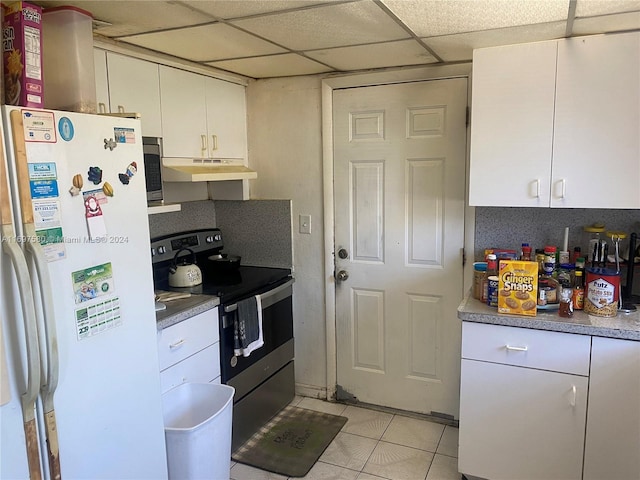 kitchen featuring white cabinets, light tile patterned floors, stainless steel appliances, and a drop ceiling