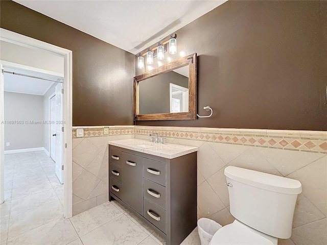 bathroom featuring vanity, toilet, and tile walls