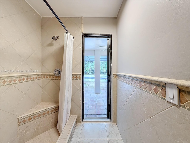 bathroom featuring curtained shower and tile walls