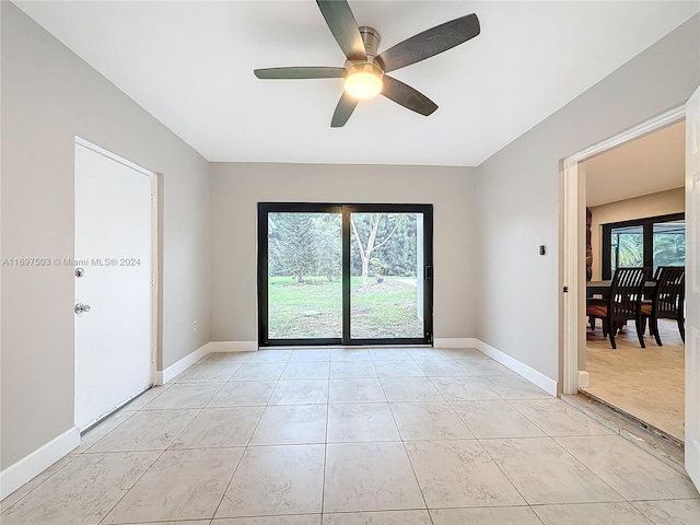 empty room featuring a wealth of natural light, ceiling fan, and light tile patterned floors