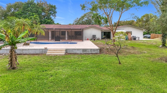 back of property with a lanai, a patio area, and a lawn