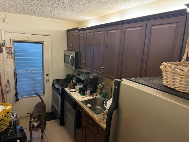20320 NE 2nd Ave Unit 27, Miami Gardens, FL 33179 - kitchen featuring appliances with stainless steel finishes, a sink, light tile patterned floors, dark brown cabinetry, and a textured ceiling