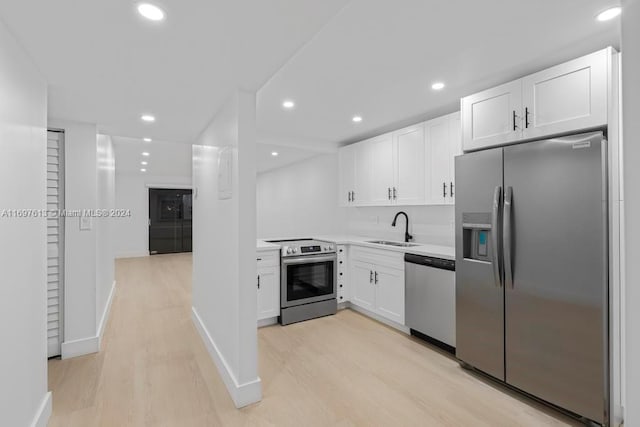 kitchen featuring white cabinetry, sink, appliances with stainless steel finishes, and light hardwood / wood-style flooring