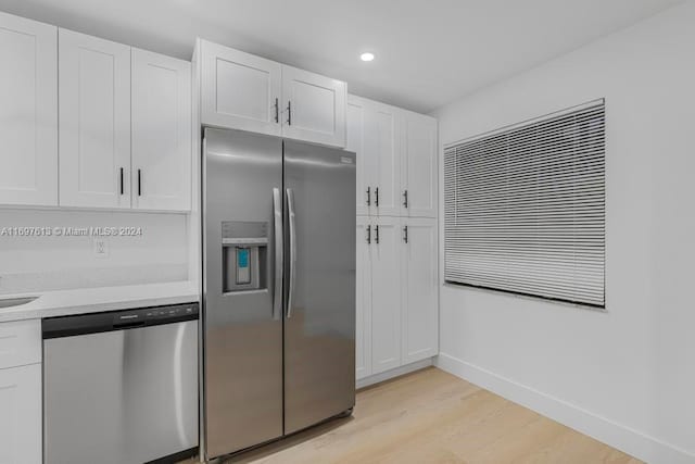 kitchen featuring appliances with stainless steel finishes, light hardwood / wood-style flooring, white cabinetry, and light stone counters