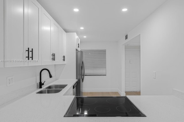 kitchen featuring white cabinets, light stone counters, sink, and appliances with stainless steel finishes