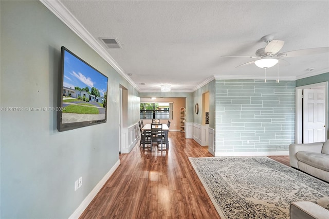 corridor featuring a textured ceiling, hardwood / wood-style flooring, and ornamental molding