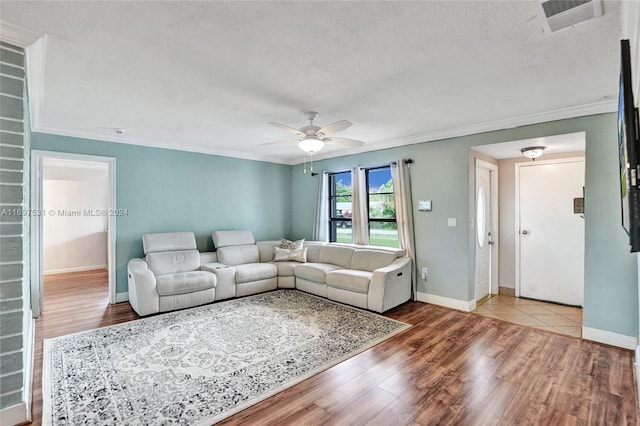 living room featuring a textured ceiling, light wood-type flooring, ceiling fan, and ornamental molding