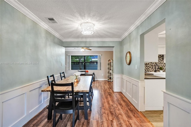 dining space with a textured ceiling, ceiling fan, wood-type flooring, and ornamental molding