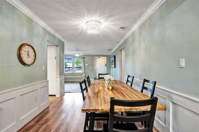 dining room with a textured ceiling, light wood-type flooring, ceiling fan, and crown molding