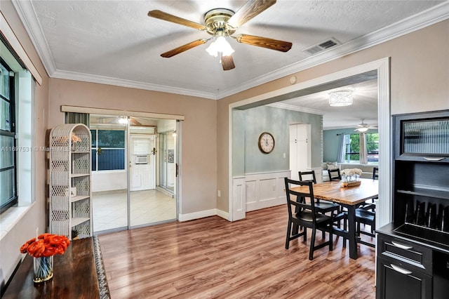 dining space featuring hardwood / wood-style floors, ceiling fan, ornamental molding, and a textured ceiling