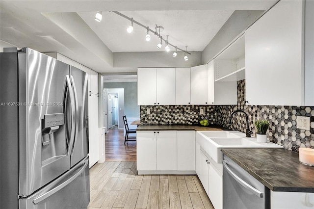 kitchen with decorative backsplash, appliances with stainless steel finishes, sink, white cabinets, and light hardwood / wood-style floors