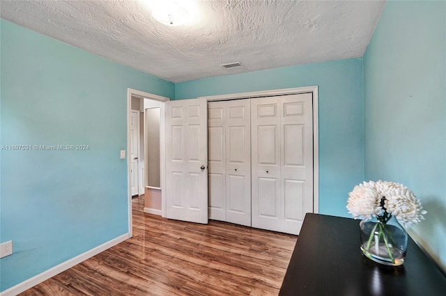 unfurnished bedroom featuring hardwood / wood-style floors, a textured ceiling, and a closet