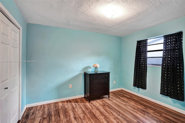 unfurnished bedroom featuring a closet, a textured ceiling, and hardwood / wood-style flooring