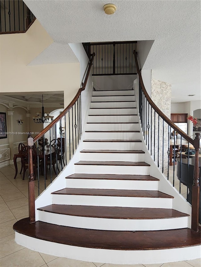 staircase featuring a textured ceiling, tile patterned floors, and a notable chandelier