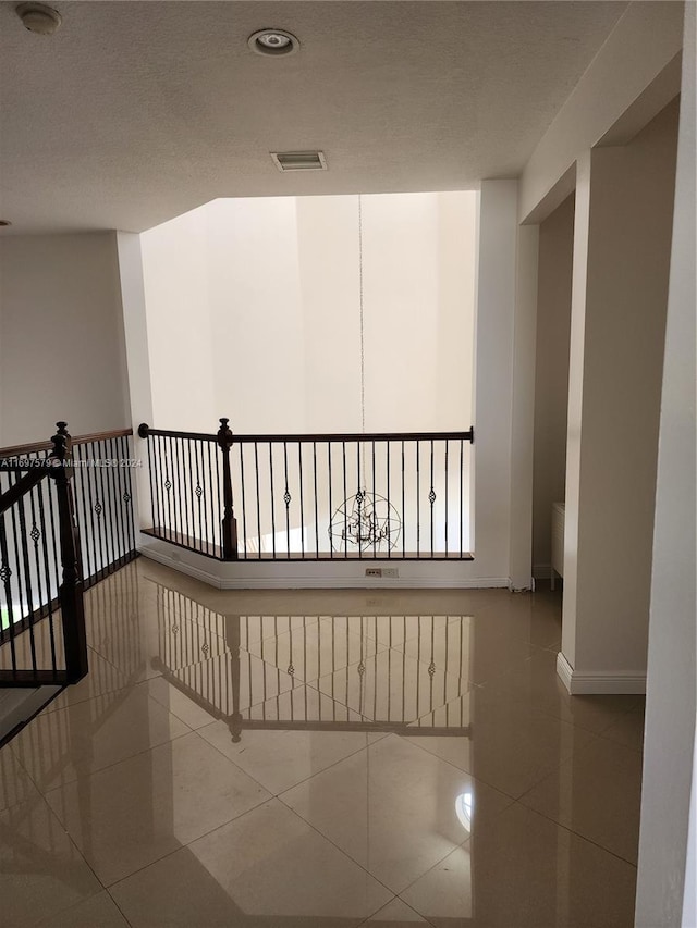 corridor featuring tile patterned flooring and a textured ceiling