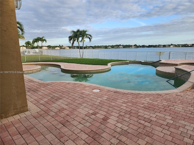 view of pool featuring a water view and a patio